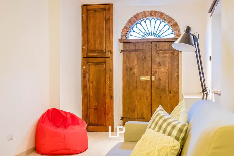 Rustic wooden door, arched brick alcove, red bean bag chair, striped throw pillow, floor lamp