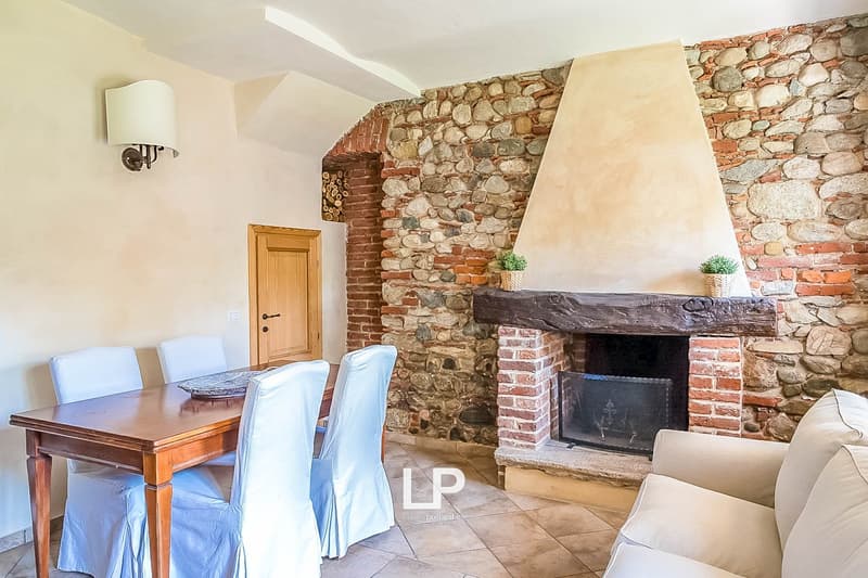 Rustic living room with stone and brick fireplace, wooden dining table, and sofa