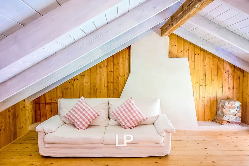 Cozy living room with wooden walls and ceiling, white sofa with pink and white striped pillows, and a fireplace