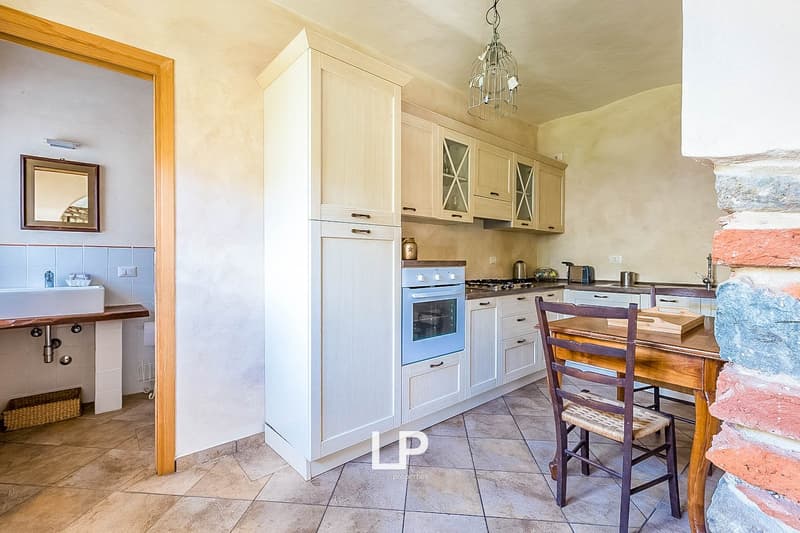 Spacious kitchen with white cabinets, wooden countertops, tiled floor, gas stove, and a dining table with chairs