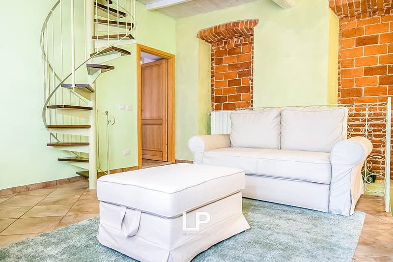 Spiral staircase, white sofa, white ottoman, brick fireplace, wooden door