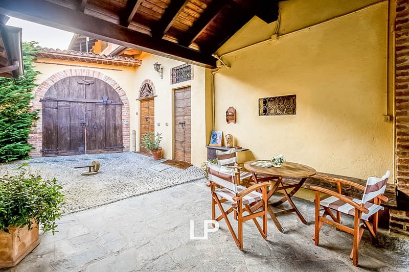 Rustic outdoor patio with wooden furniture, brick archway, and potted plants
