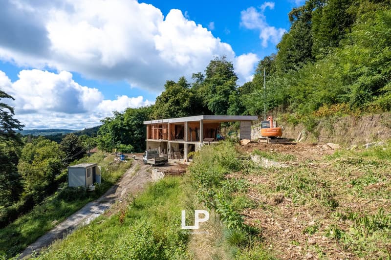 modern house, elevated, concrete foundation, wood framing, excavators and machinery present