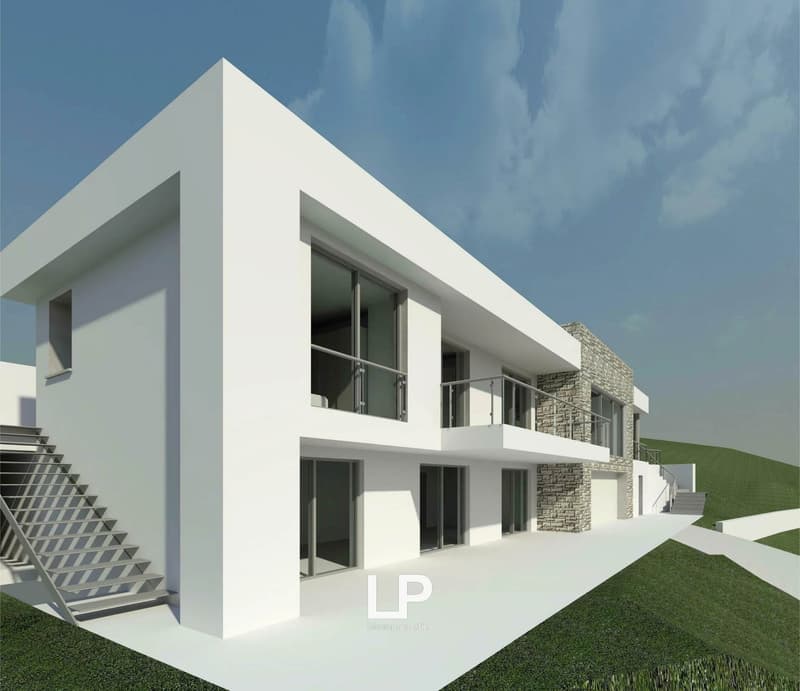 Two-story modern white house with large windows, balconies, and stone accents. The house has a minimalist, geometric design with clean lines and a flat roof.