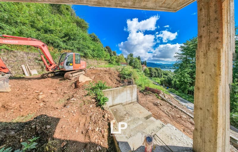 Construction site, excavator, pile of dirt, stone wall, mountain, forest