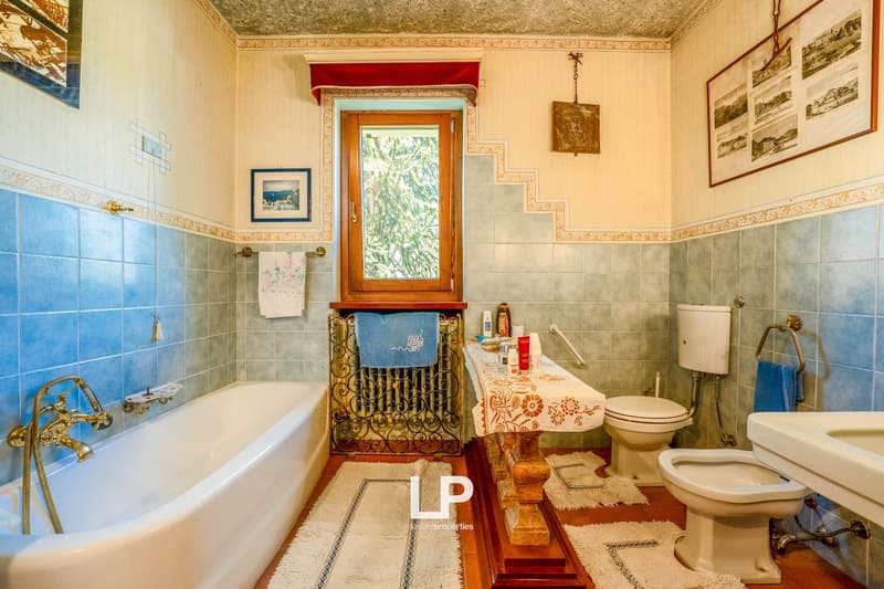 Bathtub, toilet, sink, blue and white tiles, window with curtain, radiator