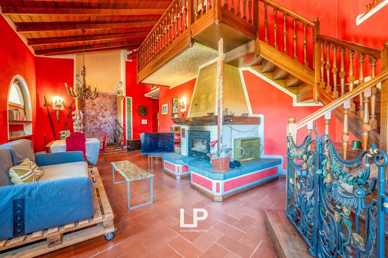 Living area with blue sofa on pallet, coffee table, large fireplace, staircase, arched window, red walls, brown wooden ceiling