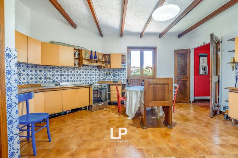 blue and white tiles, wooden ceiling beams, wooden cabinets, gas stove, wooden table, blue chairs, wooden floor, hanging light
