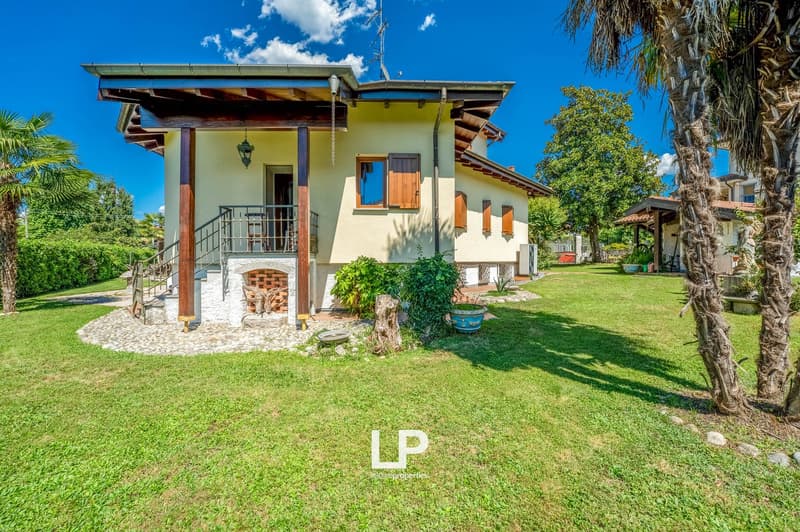 Two story house, beige walls, dark wooden roof, balcony, fireplace, garden, palm tree