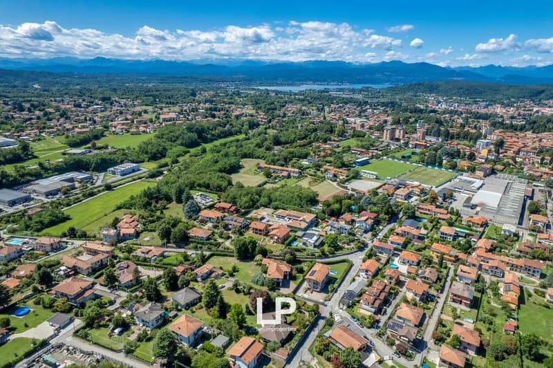 Cluster of houses, diverse building styles, red roofs, greenery, swimming pools, mountains in distance