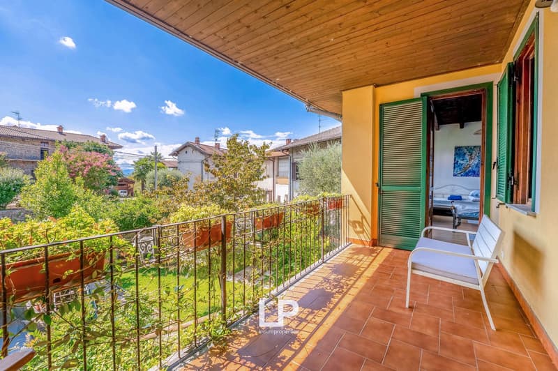 wooden roof, metal railing, terracotta floor, green window shutters, a chair, potted plants on railing