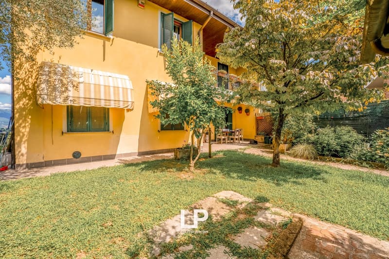 yellow house, two stories, awning, well-maintained yard, trees, table, chairs, balcony, mountain view