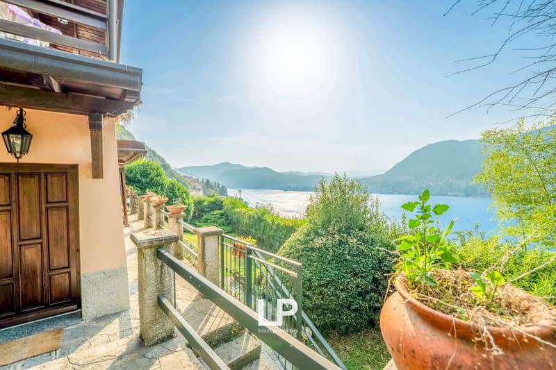 Hillside house, brown door, large window, pathway with railing, lake view, mountain view, plant pots