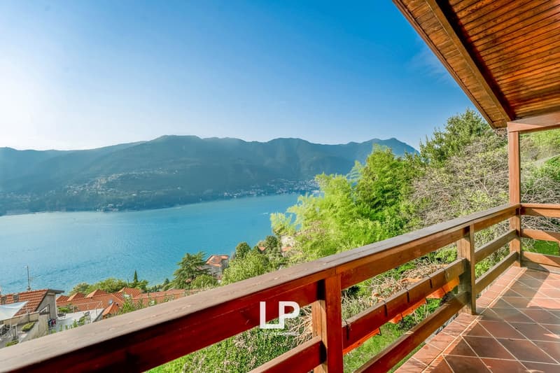 Wooden balcony with railings, sea view, mountains in the background, trees