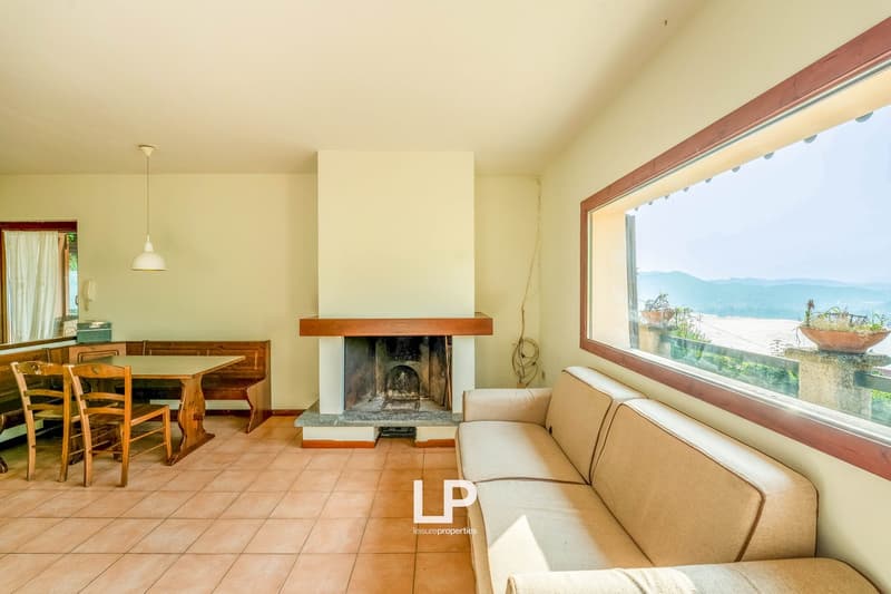 tiled floor, beige sofa, wooden dining table, fireplace, large window, wooden chairs