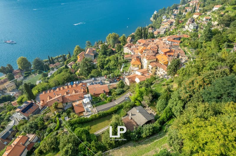 Hilltop residential area with terraced houses, red roofs, greenery, coastal waterfront.