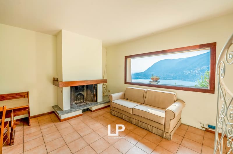 living room with couch and fireplace, large window with view, tiled floor, wooden table and chair