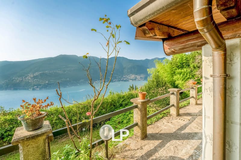 Stone walkway with wooden fence, potted plants, lamp, view of mountains and sea