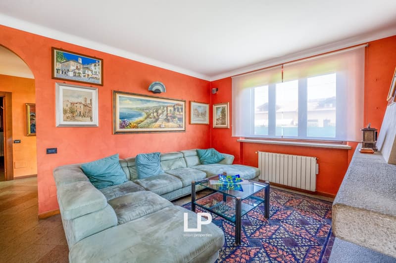 Orange walls, blue sofa, glass center table, rug, framed pictures, glass window with blinds