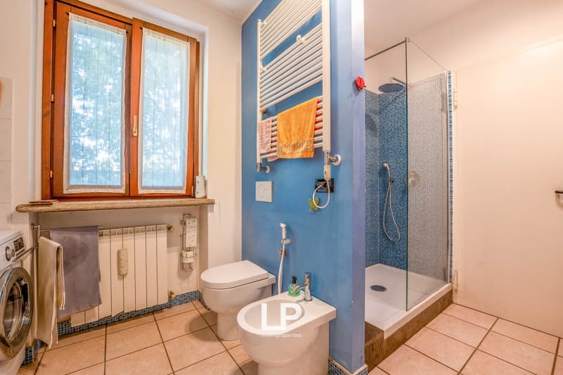 white toilet, white bidet, blue tiled wall, glass shower, white tiles, washing machine