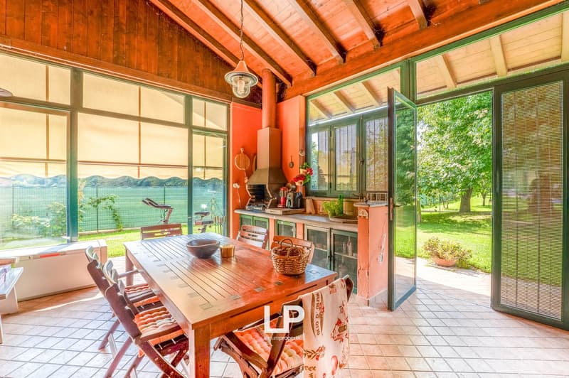 wooden table and chairs, balcony, sliding glass doors, large windows, open outdoor area, wooden ceiling, plants and trees