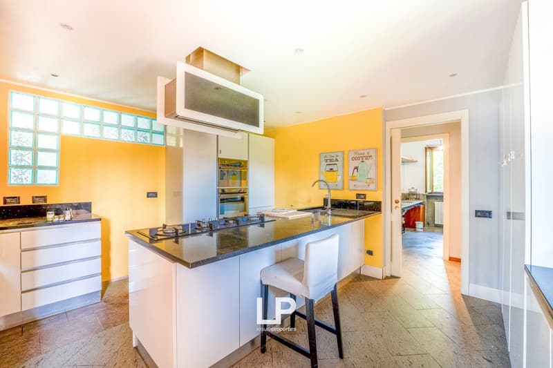 yellow wall, wooden floor, island with gas stove, countertop, cabinet, bar stool, sink, oven