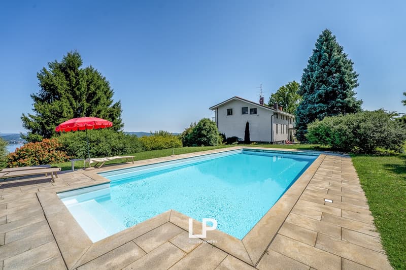 pool, sun loungers, red umbrella, green grass, plants, trees, white house