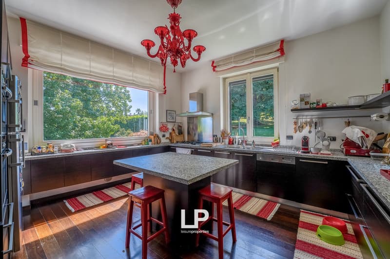 kitchen with wooden island, granite countertops, red stools, large windows, modern appliances, kitchen utensils