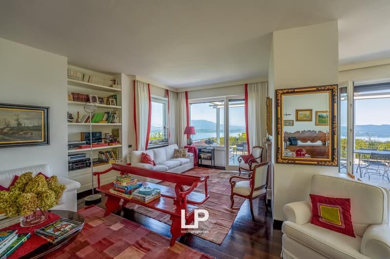 living room with couch, shelves, large windows, balcony, and books on the floor