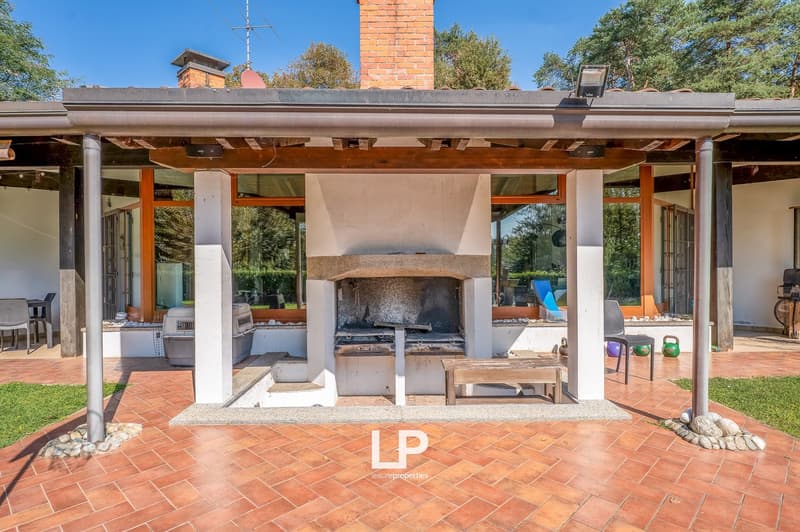 Outdoor area with a fireplace, brick chimney, wooden bench, and tiled floor.