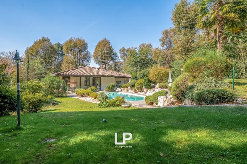 Detached house with swimming pool, surrounded by a large garden with trees and bushes