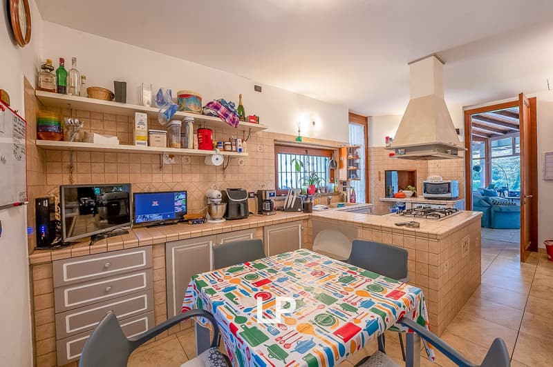 kitchen with island, gas stove, electric oven, microwave, fridge, baskets on shelves, chairs, table, 2 monitors, kitchen tools