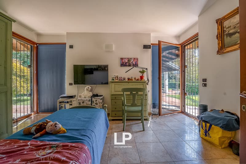 blue bedding, teddy bear, chair, desk, TV mounted on wall, large windows