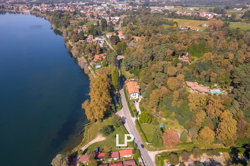 Aerial view of a town near a river, with several houses and buildings, surrounded by trees and greenery.