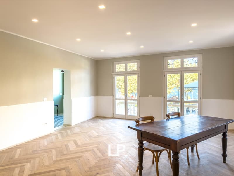 large room with parquet flooring, wooden table, wooden chairs, large windows, balcony with view