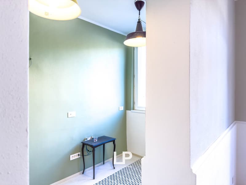 small room with light blue walls, white tile floor, power outlets, a small black table, and two lamps