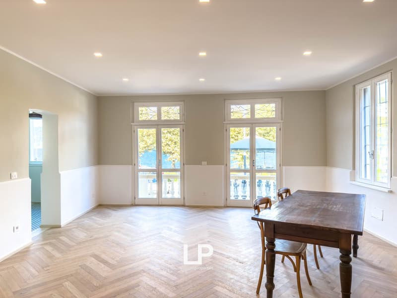 room with wooden floor, white walls, dining table and chairs, large windows with doors leading to balcony, no furniture
