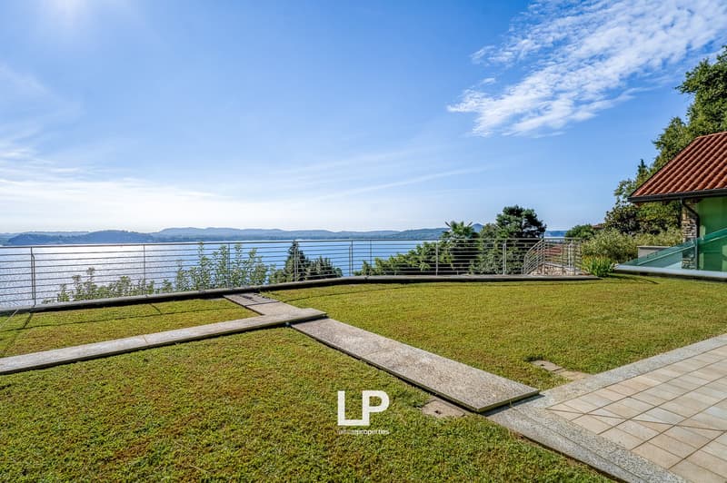 lawn, stone pathways, fence, water body, mountains in the background
