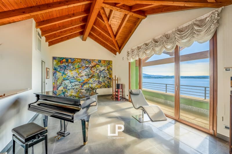 wooden beams on ceiling, modern furniture, piano, large painting, lounge chair, floor to ceiling windows, balcony, lake view