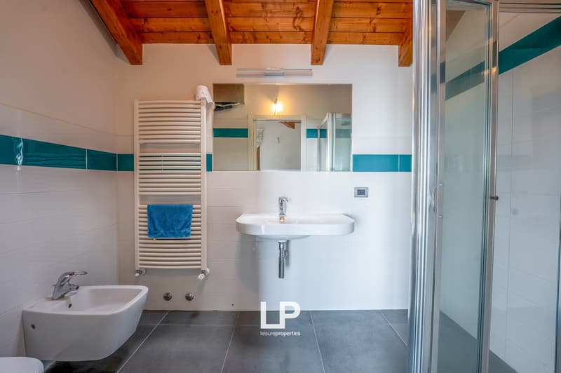 white tiles, blue tiles, glass shower, white basin, towel rack, mirror