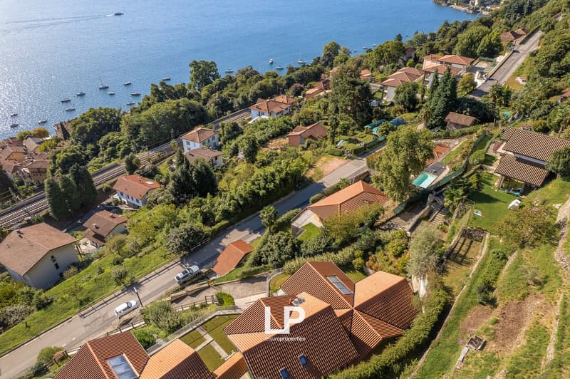 Houses along a coast, tiled roofs, greenery, pool, docked boats