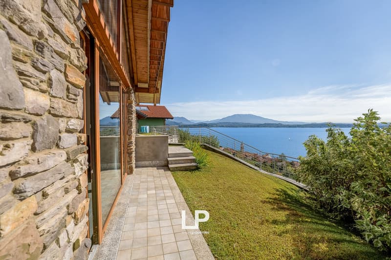 Stone exterior, wooden balcony, glass wall, large grassy yard, fenced balcony, lake view