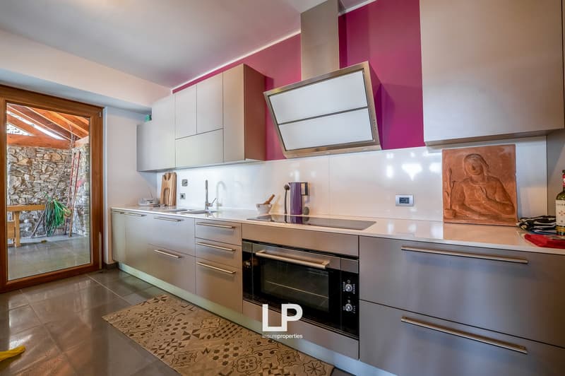 modern kitchen with white cupboards, stainless steel appliances, wooden flooring, pink wall, white countertop, picture, sink, dishwasher, washing machine