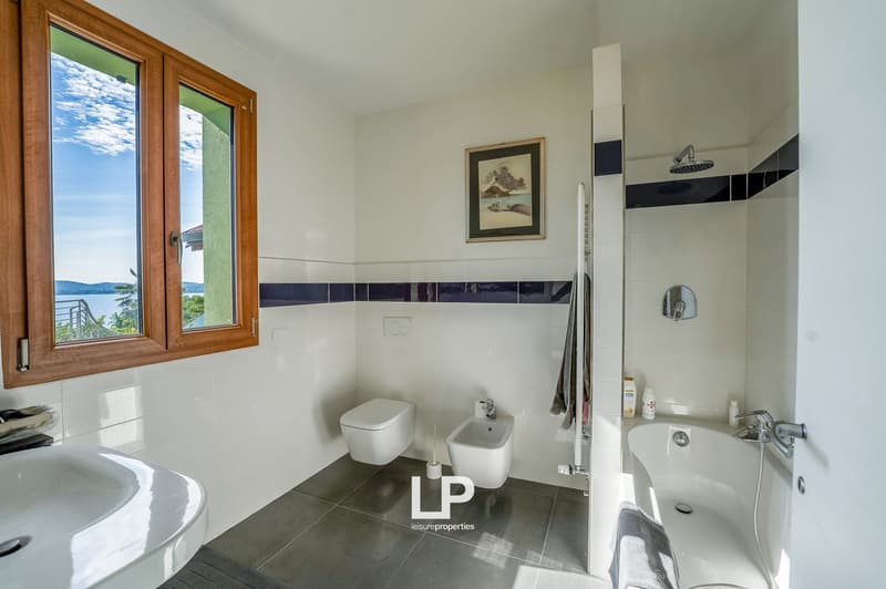 Bathroom with toilet, bidet, bathtub, white sink, and window with scenic view