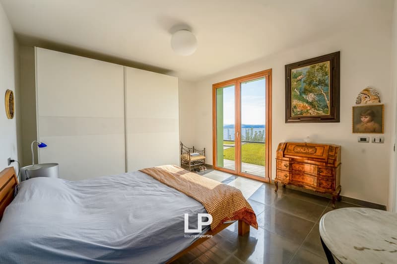 large bed, wooden bedhead, large sliding door to terrace, white walls, parquet floor, painting, marble desk