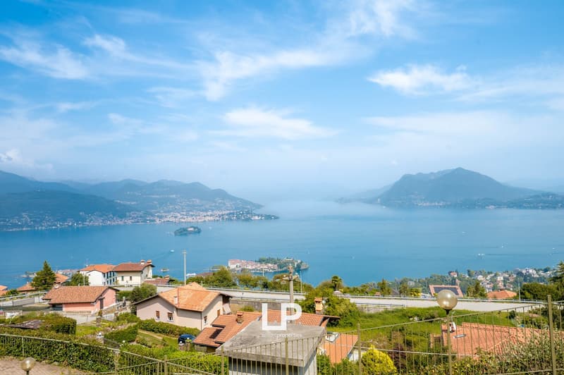 hillside location, multiple houses, distant sea view, mountain range, trees, clear blue sky