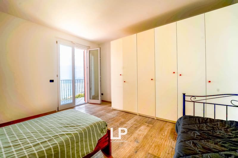 2 single beds, closet with red knobs, double glass doors leading to balcony with ocean view
