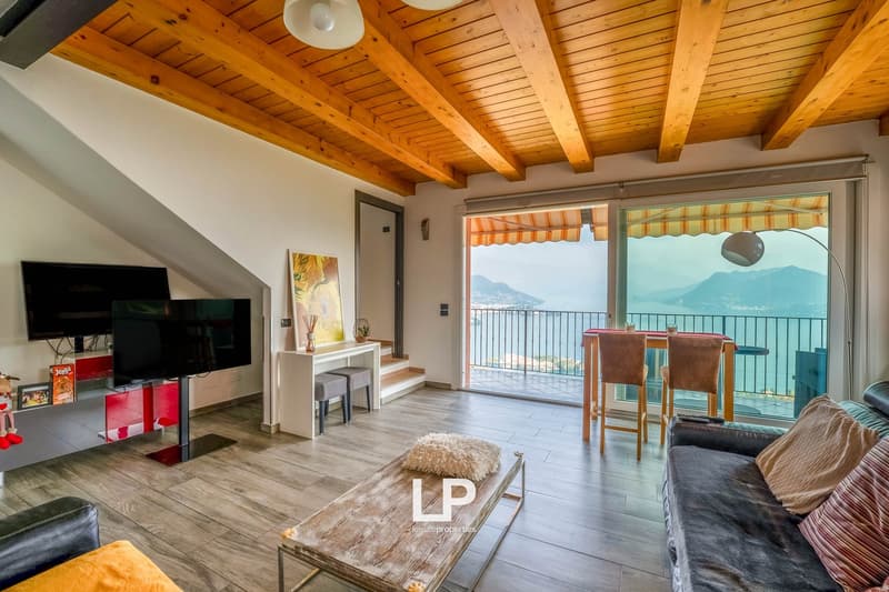 wooden ceiling, gray walls, hardwood floors, coffee table, sofa, TV stand with 2 TVs, balcony with chairs and table, scenic lake view