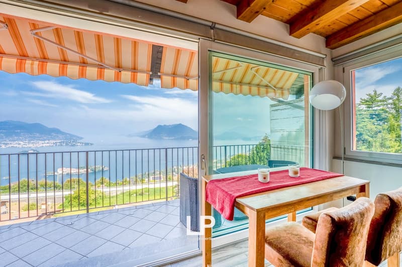 wood floor, glass doors, large windows, balcony with railing, table, chairs, lamps, red tablecloth, sea view