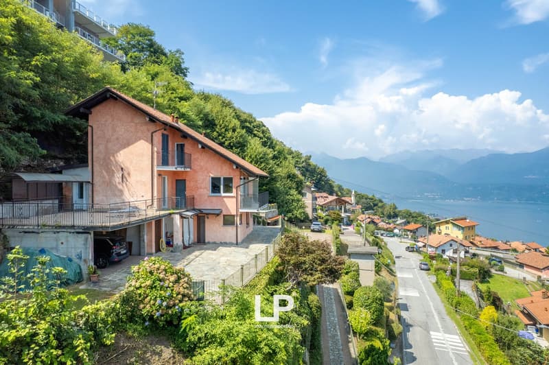 Situated on a hillside, this 2 story home features a sloping roof, balconies with railings, a parking area, and lush greenery. It is surrounded by other buildings, trees, and offers a scenic view of the ocean and mountains.